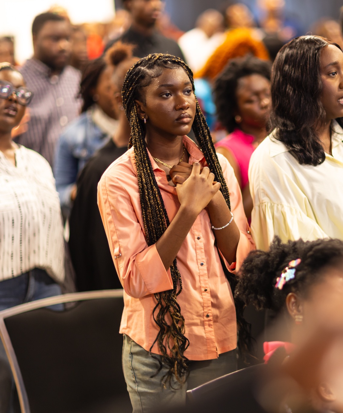 Young woman praying during worship service at the Non-Denominational Church in Houston, TX
