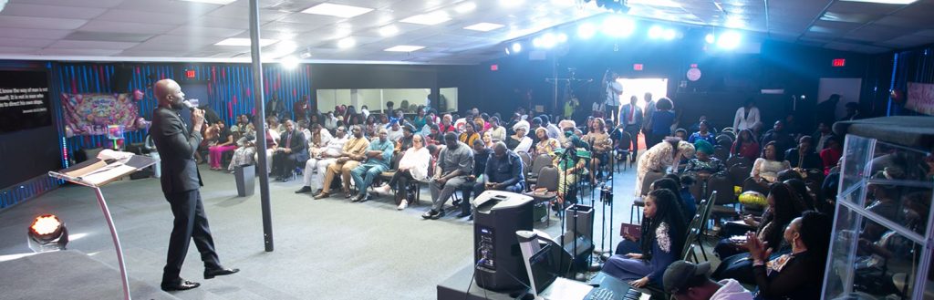 Pastor preaching to congregation during Sunday service at OFM Houston