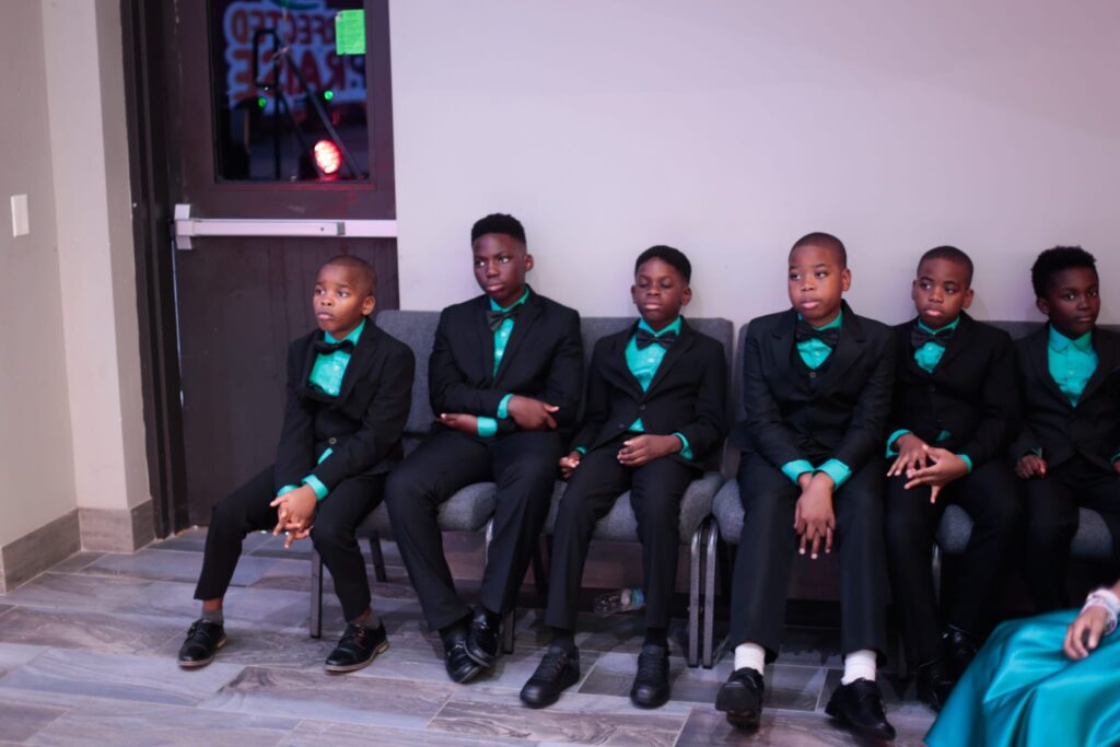 Boys in Black Suits with Teal Bow Ties Preparing for Their Children’s Ministry Performance